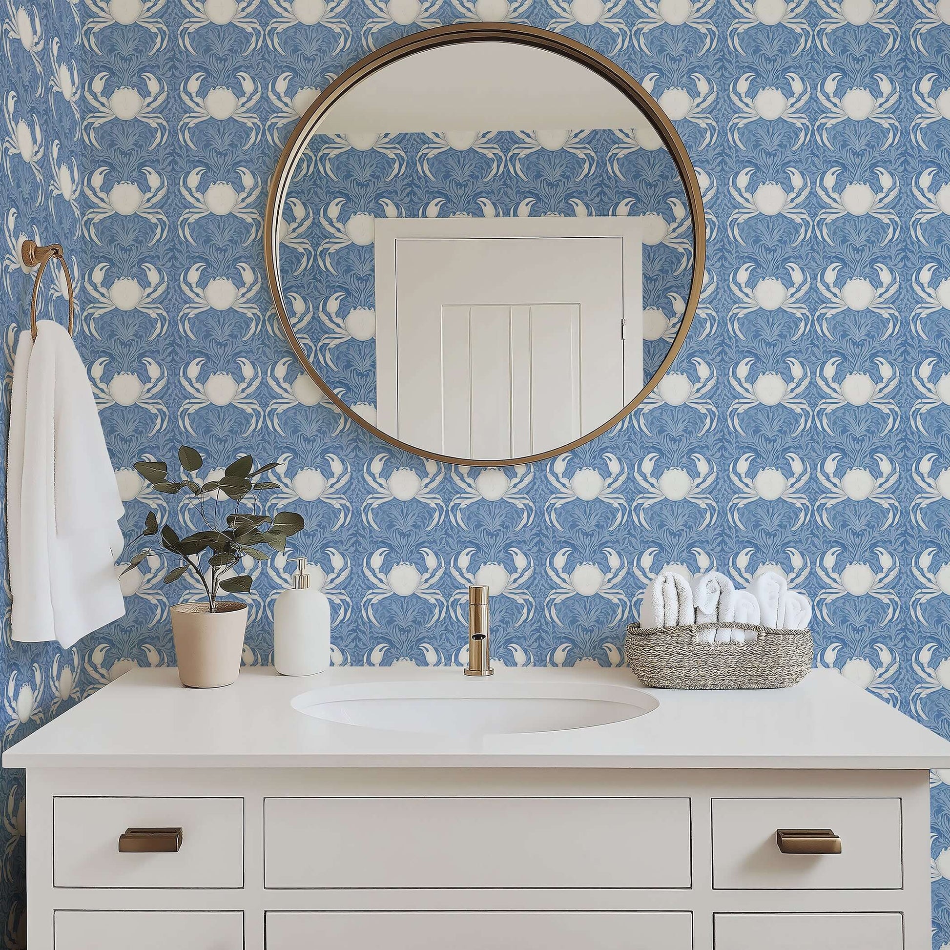 Elegant blue coastal wallpaper featuring white crabs and sea foliage in a bathroom with a round mirror and modern vanity.