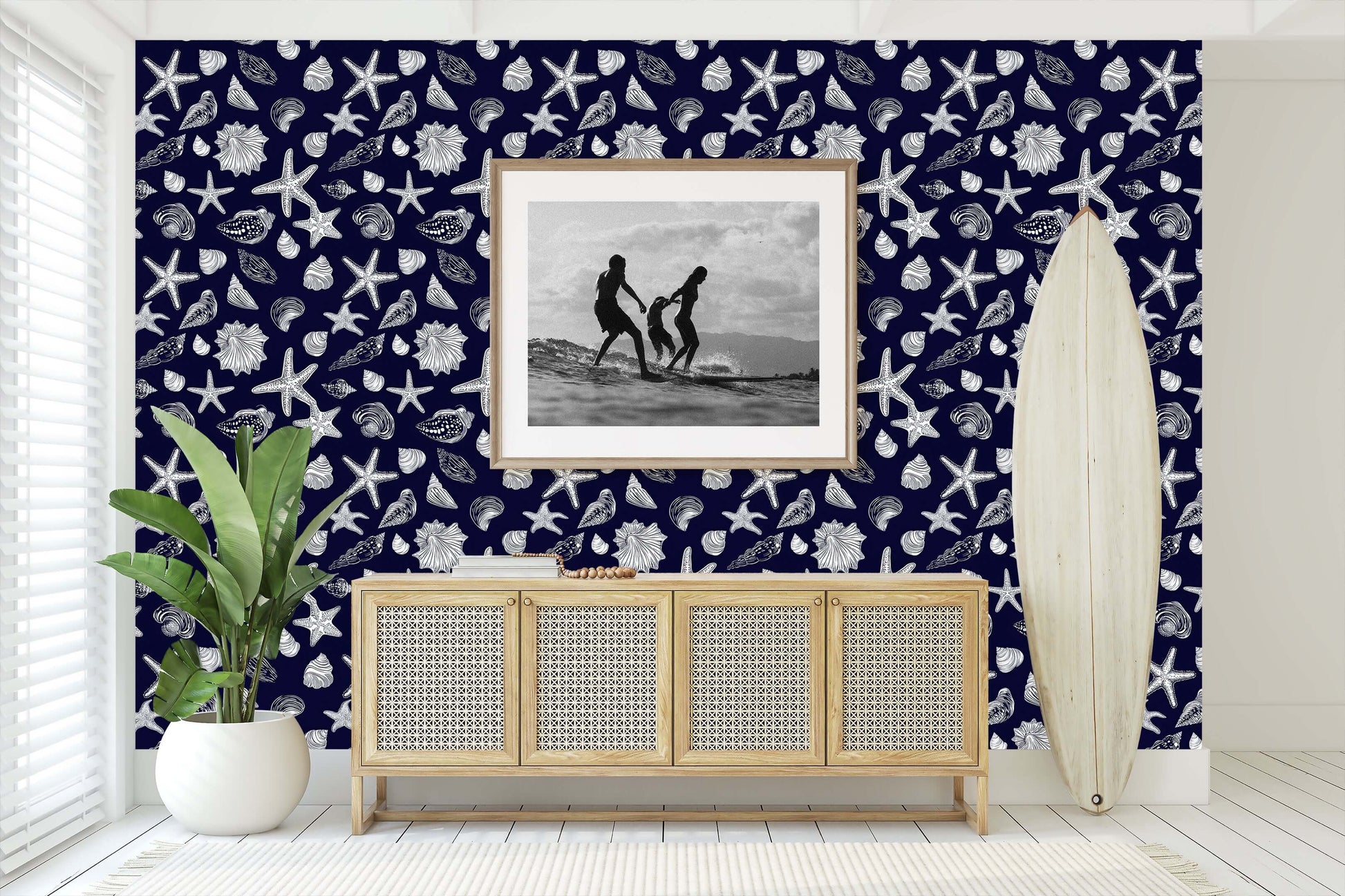 Coastal room with navy wallpaper featuring white seashells and starfish, complemented by beach-themed decor and a surfboard.