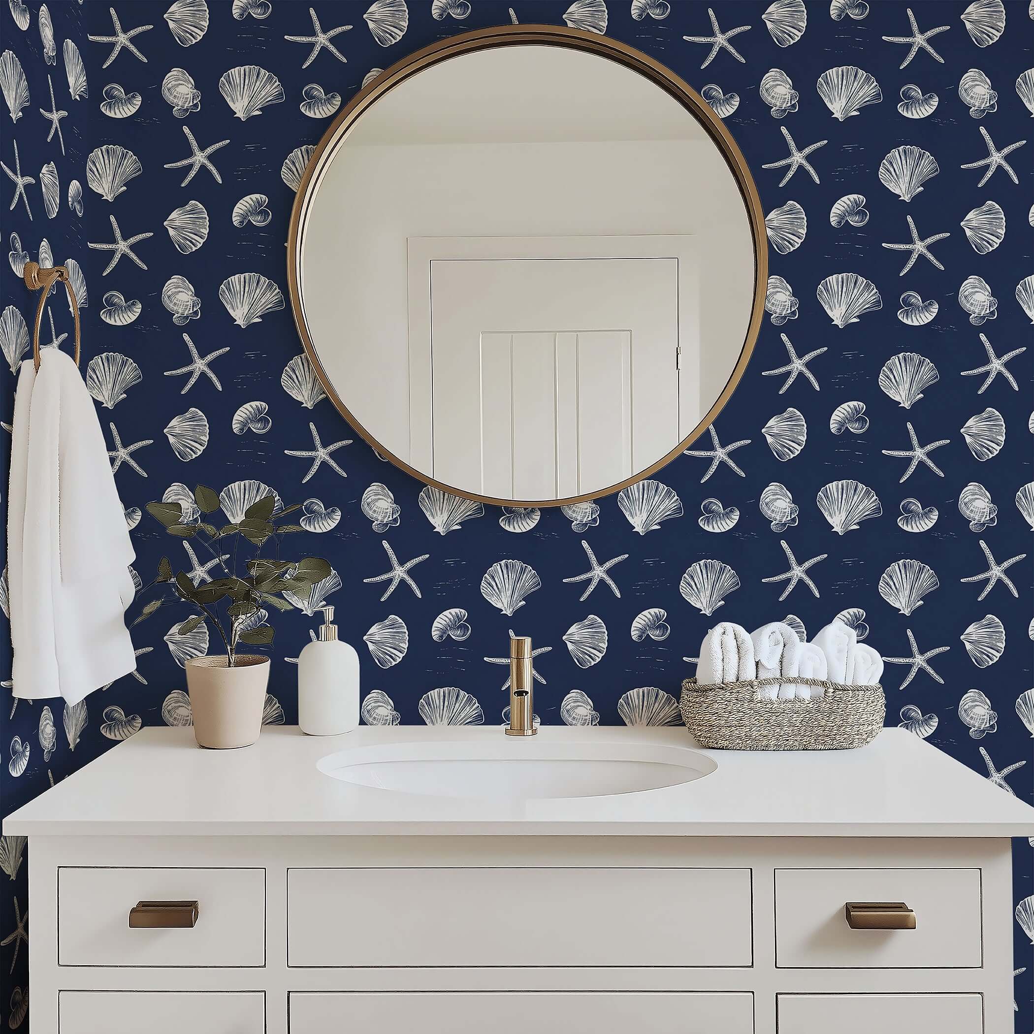 Bathroom with navy coastal wallpaper featuring white starfish and seashells, complementing a round mirror and elegant sink area.