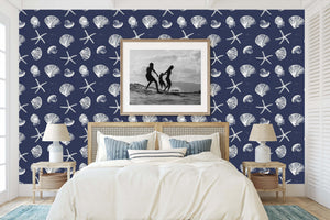 Bedroom with Coastal Inked Classics wallpaper featuring starfish and seashells on a navy background, enhancing a beach-themed decor.
