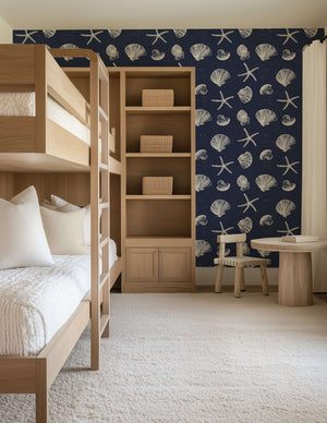 Coastal Inked Classics wallpaper featuring starfish and seashells on a navy background in a cozy, beach-inspired bedroom.