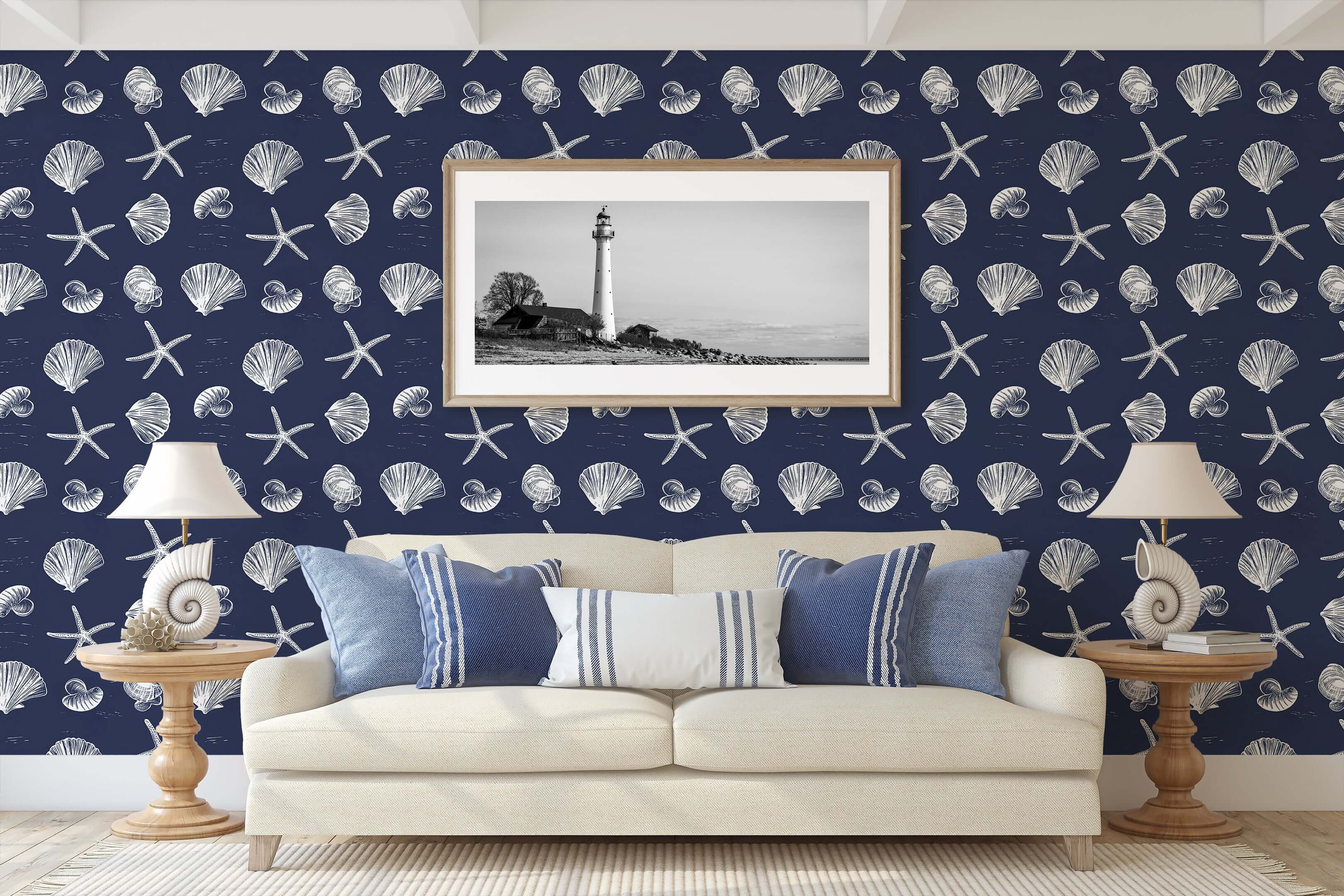 Navy coastal wallpaper with white seashells and starfish, ideal for beach-themed rooms, shown behind a beige sofa with nautical decor.