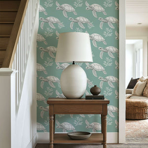 Wall with 'Turtle Drift' wallpaper featuring white sea turtles, coral, and seaweed on soft sage green for a coastal touch.