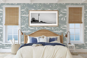 Seafoam Shores wallpaper featuring sailboats and palm trees in a coastal bedroom with a view of the ocean, enhancing nautical elegance.