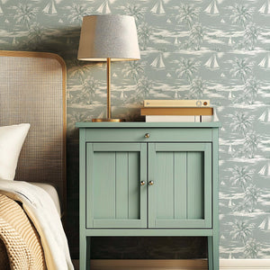 Seafoam Shores wallpaper featuring boats and palm trees in a coastal design in a bedroom setting with a green nightstand.