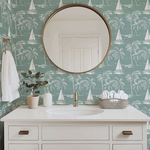Serene bathroom with Harbor Escape wallpaper featuring boats, palm trees, and coastal silhouettes in calming seafoam green tones.