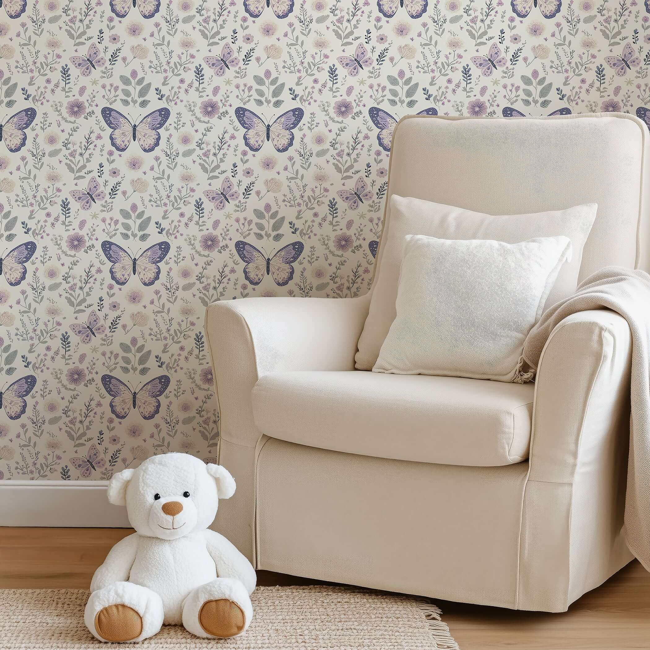 Enchanted Floral Flight wallpaper with butterflies and florals adorns a cozy nursery, featuring a soft beige chair and teddy bear.
