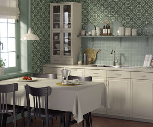 Classic kitchen with green geometric floral wallpaper, white cabinets, and a table set for dining.
