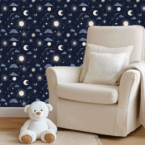 Cozy nursery with 'Night and Lullaby' wallpaper featuring navy skies, crescent moons, stars, clouds, and a plush teddy bear.