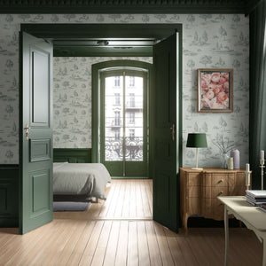Lush Pastoral Toile II Wallpaper in a bedroom with green trim, wooden floors, and a blend of French toile and countryside landscape designs.