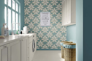Mid-century modern wallpaper with large white flowers on a teal background, bringing retro charm to a stylish laundry room.