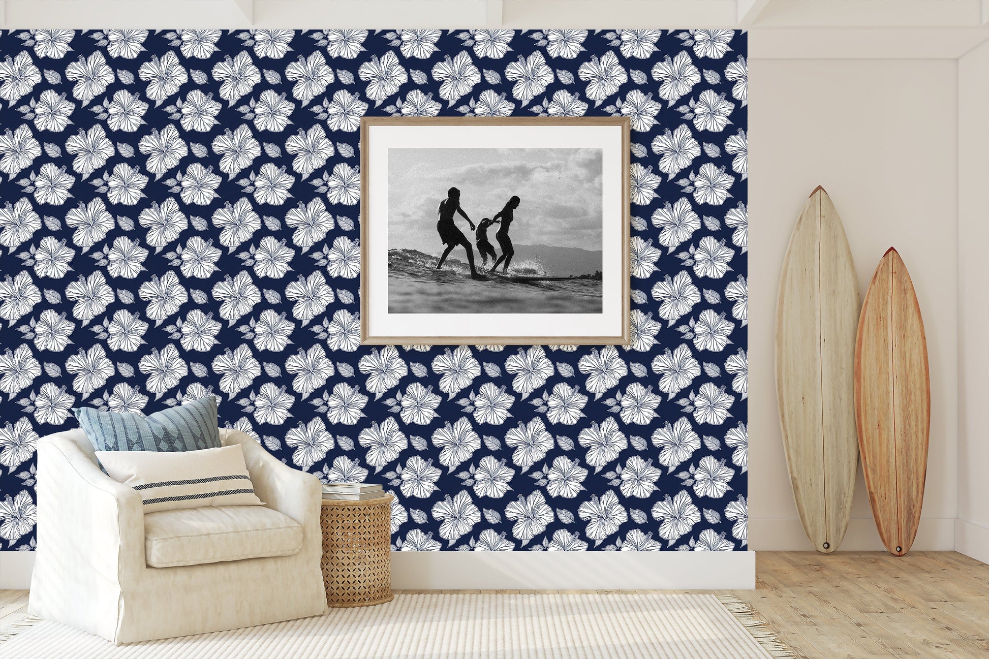 Coastal living room with Midnight Hibiscus Elegance wallpaper featuring white hibiscus flowers on a navy background, surfboards, and seating area.