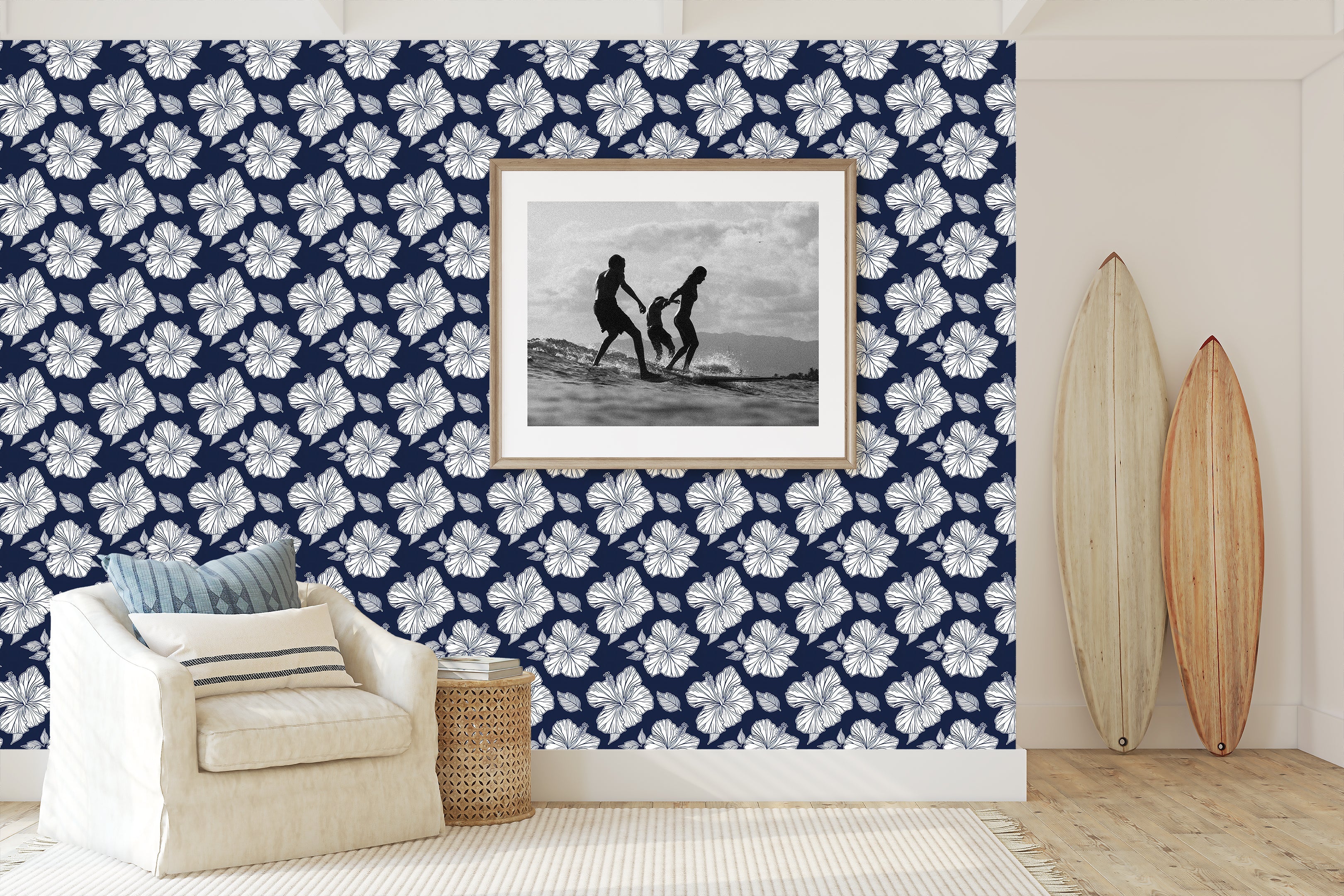 Coastal living room with Midnight Hibiscus Elegance wallpaper featuring white hibiscus flowers on a navy background, surfboards, and seating area.