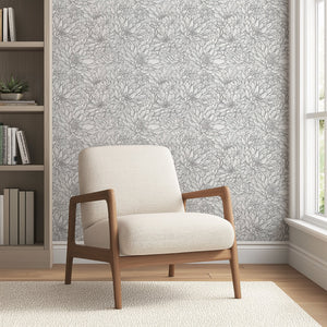 Monochromatic black and white floral wallpaper with hand-drawn chrysanthemums, featuring a modern chair in a cozy interior setting.