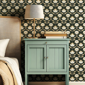 Art Nouveau floral wallpaper with ivory flowers on dark green, complementing vintage decor and bedside table in cozy room setting.