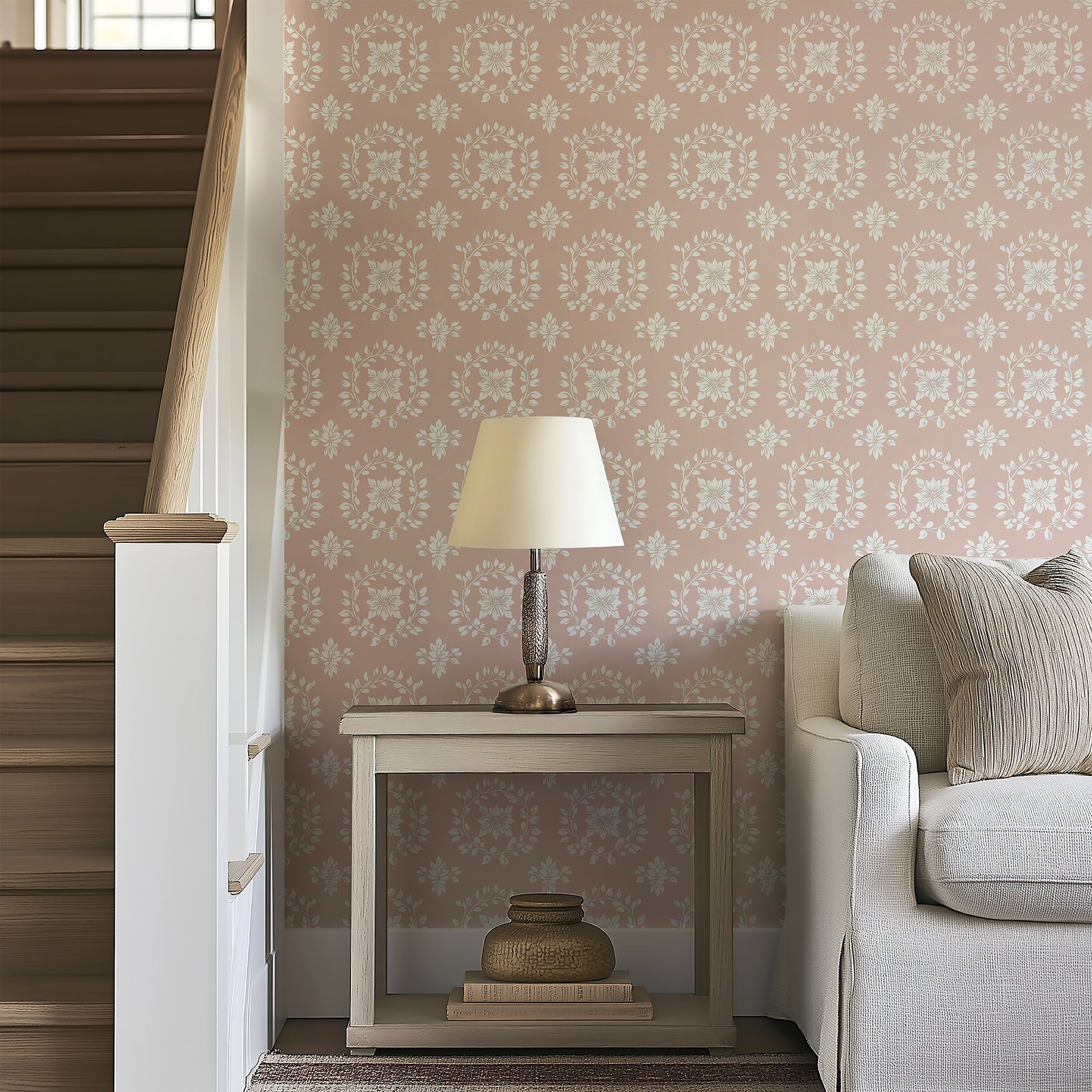 Elegant floral wreath wallpaper in muted ivory and gray on blush background, enhancing a cozy living room setting with traditional allure.