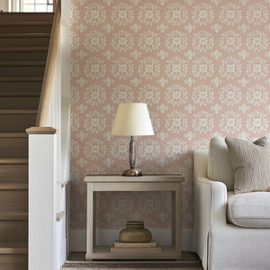 Elegant floral wreath wallpaper in muted ivory and gray on blush background, enhancing a cozy living room setting with traditional allure.