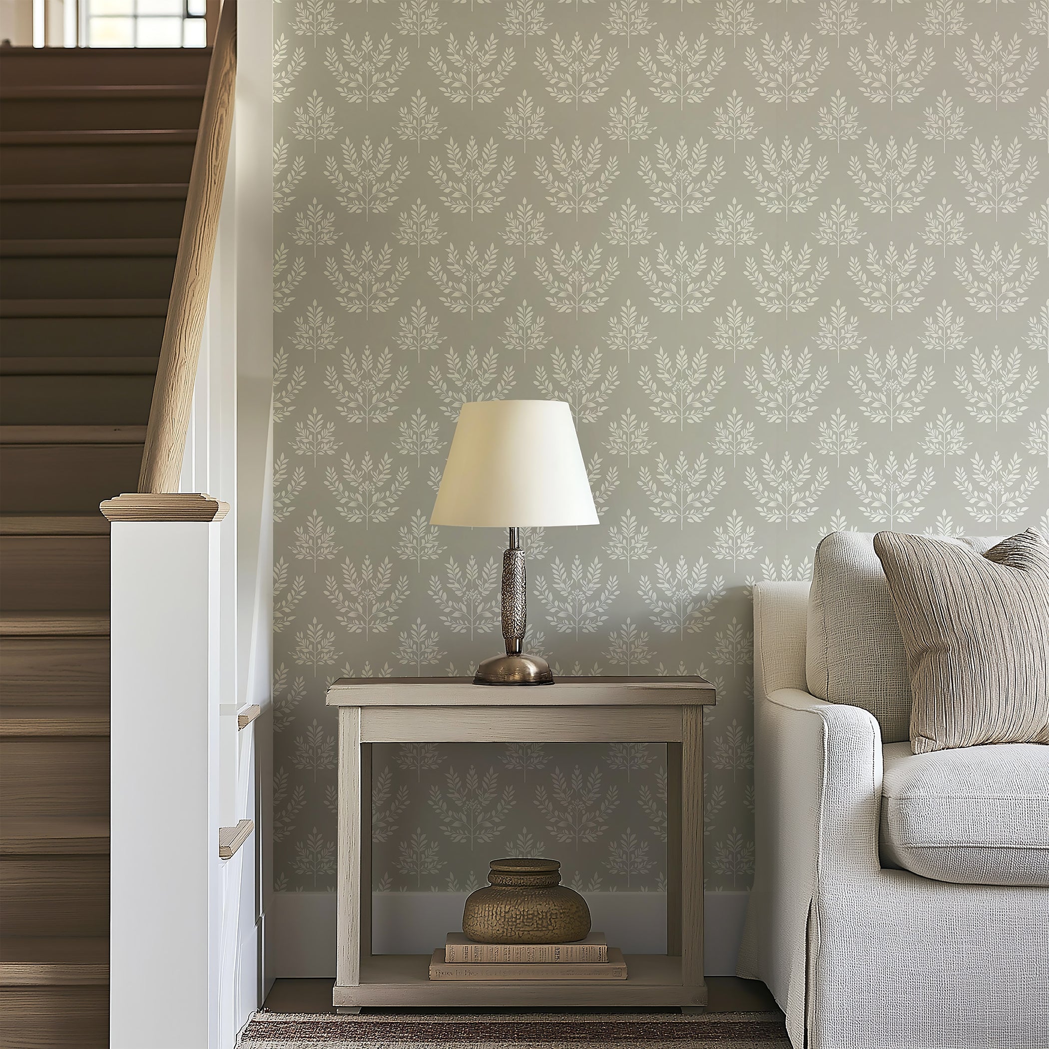Elegant laurel wreath patterned wallpaper in ivory and gray adds traditional charm to living room with a modern sofa and table lamp.