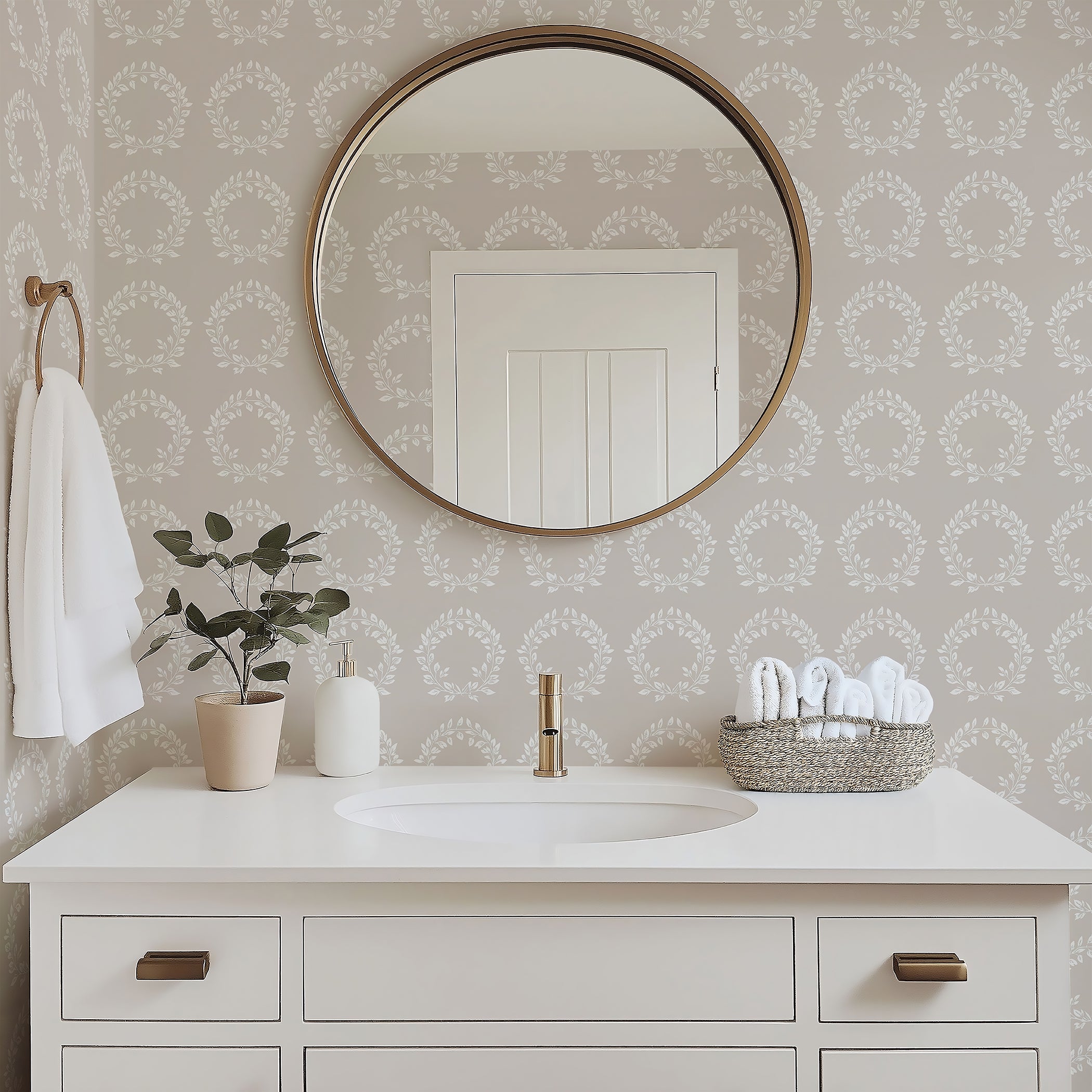 Bathroom with Traditional Wreath Harmony Wallpaper featuring white laurel wreaths on taupe background, round mirror, and white vanity.