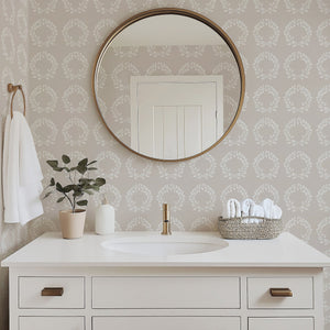 Bathroom with Traditional Wreath Harmony Wallpaper featuring white laurel wreaths on taupe background, round mirror, and white vanity.
