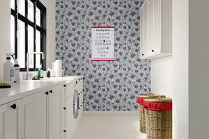 Inked Petals monochrome floral wallpaper in a modern laundry room with white cabinets and stylish storage baskets.