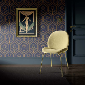 Art Deco geometric wallpaper with golden hex blossoms on navy, modern chair, and decorative wall art.