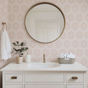 Geometric rose gold prism wallpaper in a modern bathroom with art deco style, white vanity, and round mirror.
