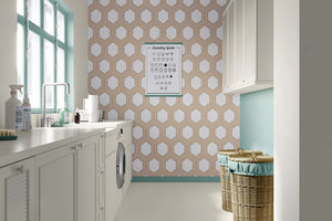 Art Deco geometric wallpaper with bronze hexagons on white background, enhancing modern laundry room decor.