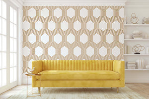 Art Deco geometric wallpaper with bronze hexagonal pattern on white, enhancing a modern living room with a yellow sofa.