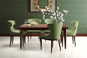 Art Deco dining room with geometric wallpaper, featuring emerald and gold hexagons, green chairs, and a wooden table.