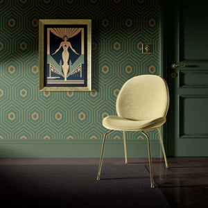 Art Deco geometric wallpaper with emerald and gold hexagons, featuring a modern chair and framed artwork, perfect for accent walls.