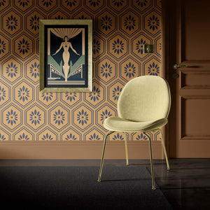 Art deco geometric wallpaper with black floral hexagons on ochre background, paired with a modern chair and framed artwork.