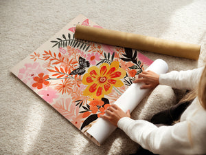Person unrolling a vibrant floral wall art print featuring flowers and butterflies in warm colors.