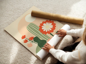 Person unrolling a wall art print of cactus and flowers in warm tones, depicting modern boho art.