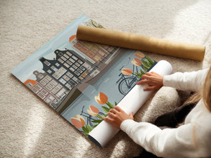 Person unrolling a Vintage Amsterdam art print featuring canals, tulips, bicycles, and Dutch architecture.