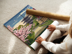 Person unrolling a vintage travel poster of cherry blossoms and temples in Kyoto, Japan.