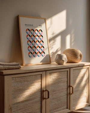 Bauhaus-inspired wall art print with geometric pattern in retro colors on a wooden console.