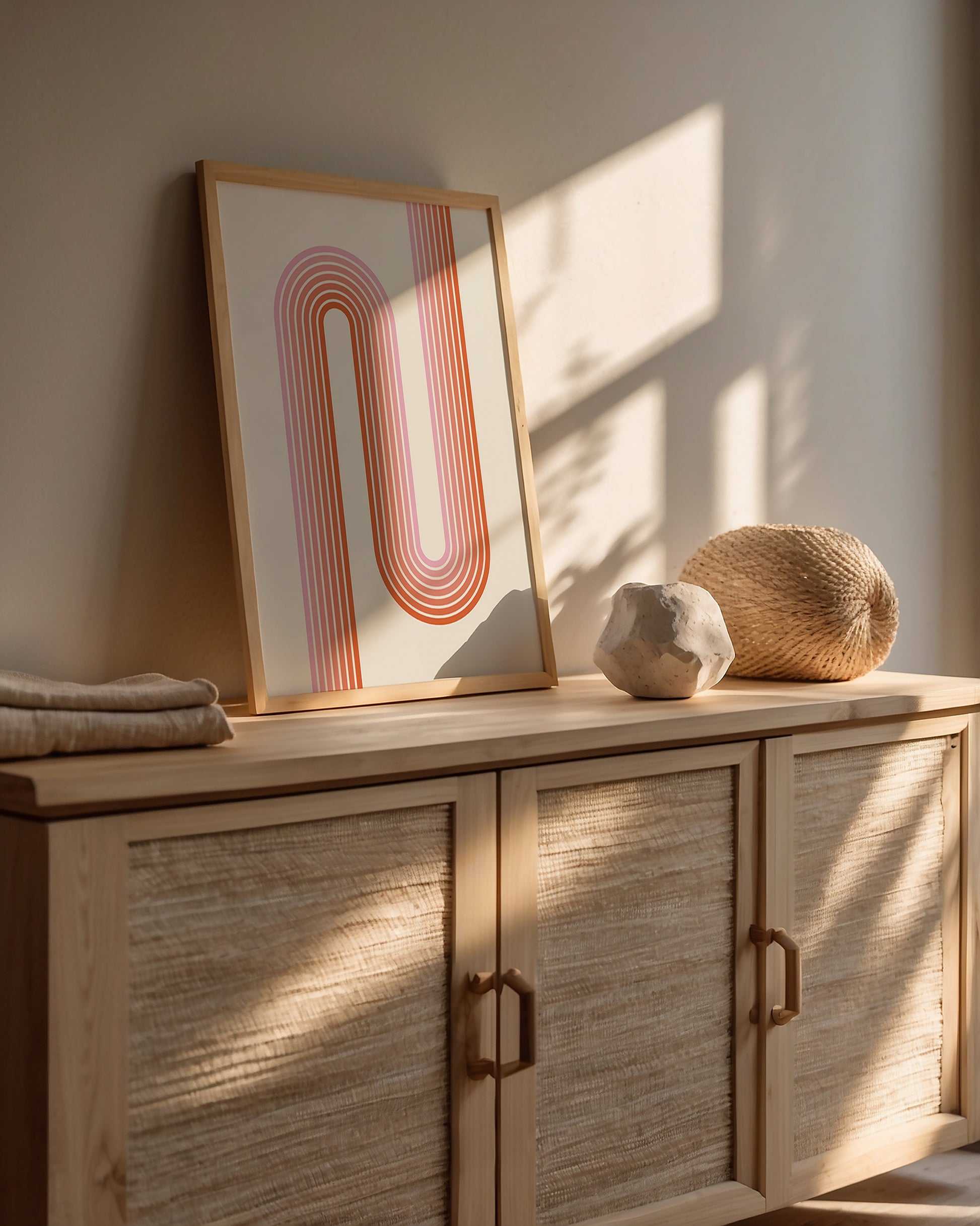 Sunset Stripes wall art print showcasing Bauhaus design with warm coral and blush lines in a modern interior.