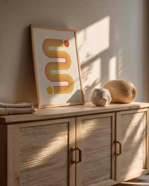 Bauhaus-inspired abstract art print with sunset-toned lines and vivid circles in warm interior setting.