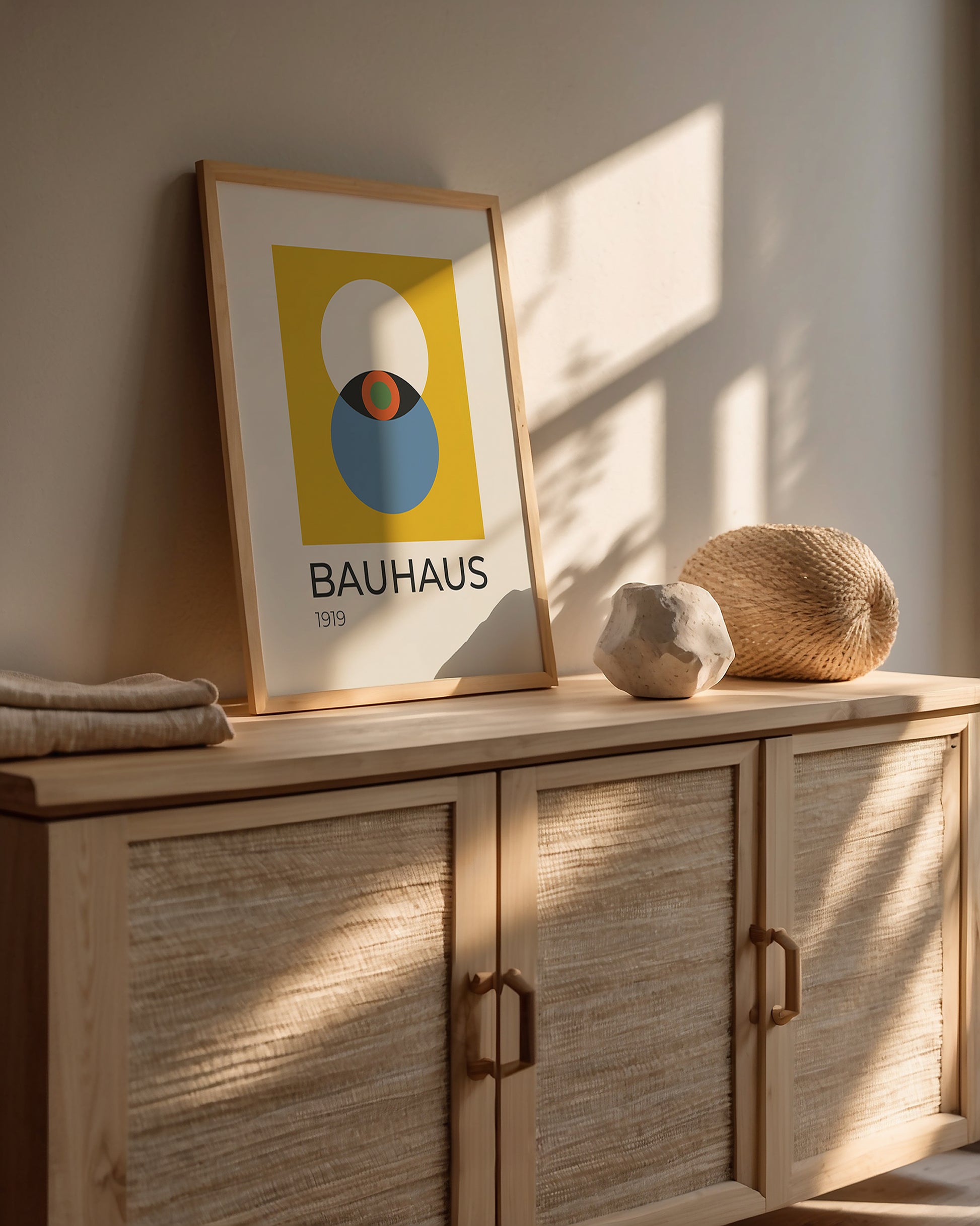 Bauhaus wall art print featuring an abstract eye design in bold colors, displayed on a modern wood cabinet.
