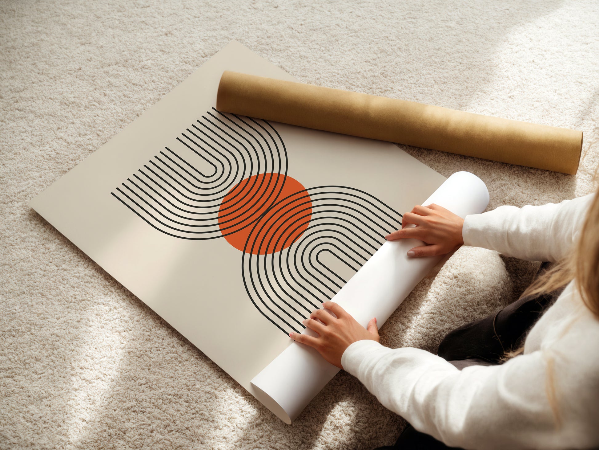 Person unrolling a Bauhaus-inspired wall art print featuring geometric lines and a terracotta sun.