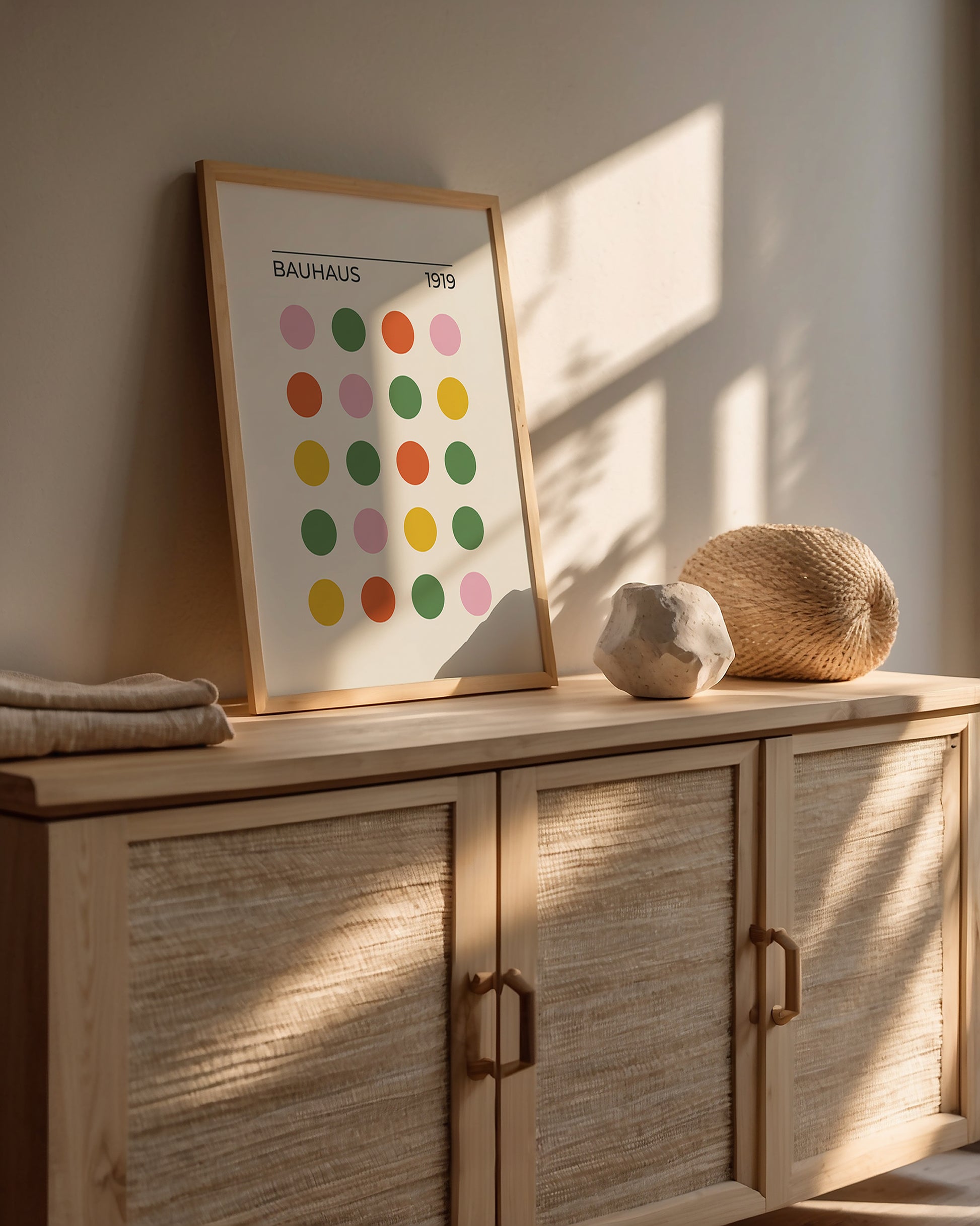 Bauhaus modern art print with colorful dots on wall above natural wood cabinet and textured decor, showcasing minimalist design.