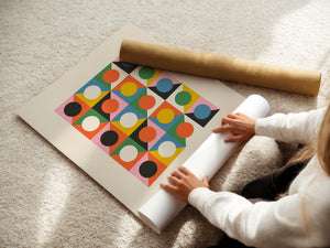Person unrolling a Bauhaus art print featuring geometric shapes and vibrant colors on a light carpet.