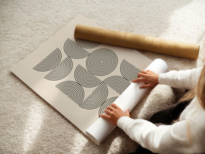 Person unrolling a Bauhaus-inspired art print titled 'Structured Echoes' with geometric patterns and concentric circles.