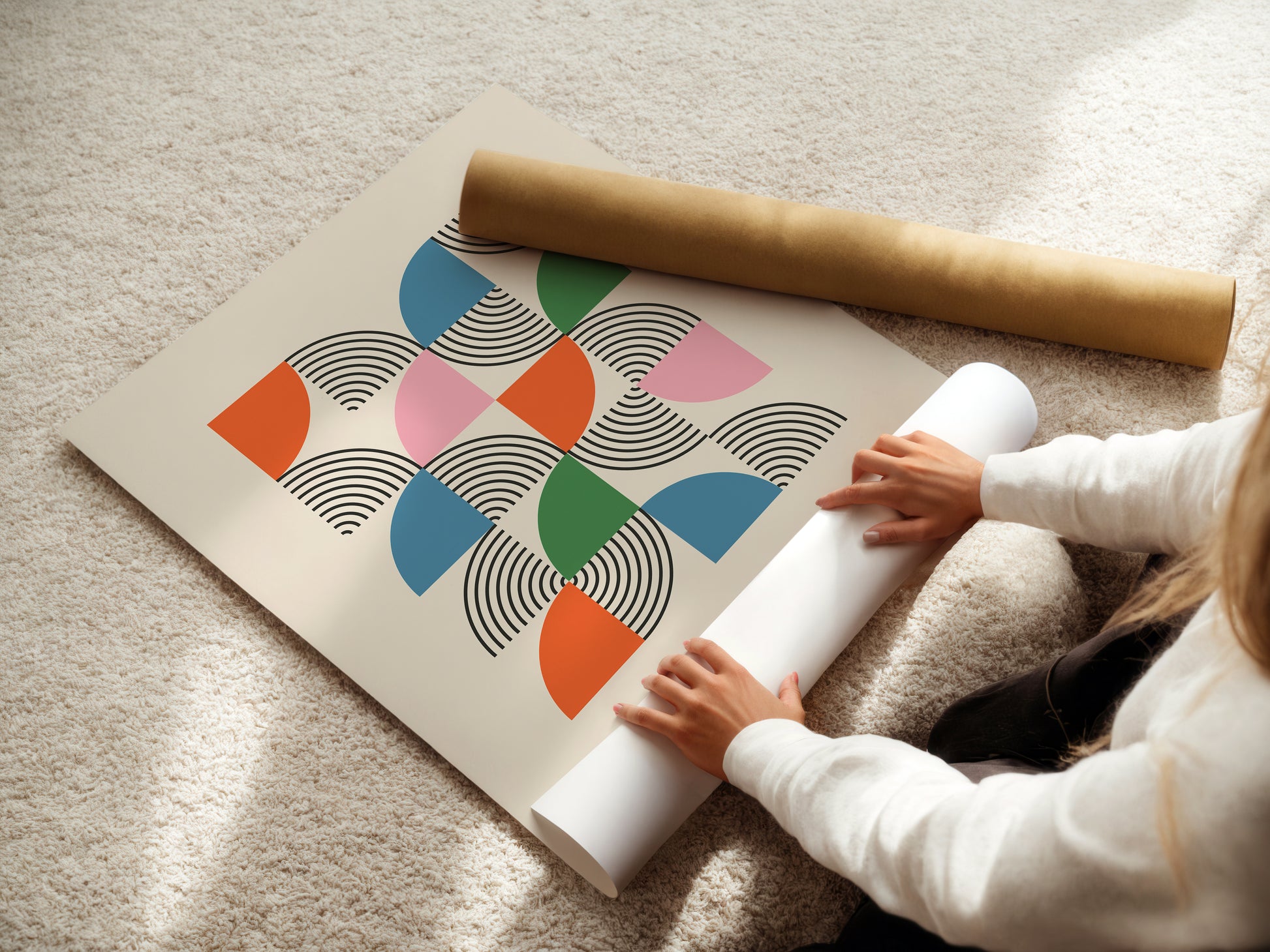 A person unrolling the Modernist Mosaic art print featuring colorful semicircles and black linework, inspired by Bauhaus design.