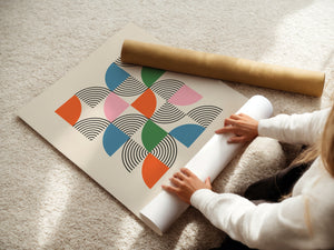 A person unrolling the Modernist Mosaic art print featuring colorful semicircles and black linework, inspired by Bauhaus design.