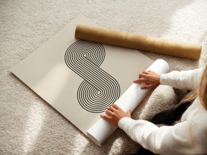 Person unrolling Bauhaus-inspired Infinity Loop wall art print with concentric lines on a neutral background.
