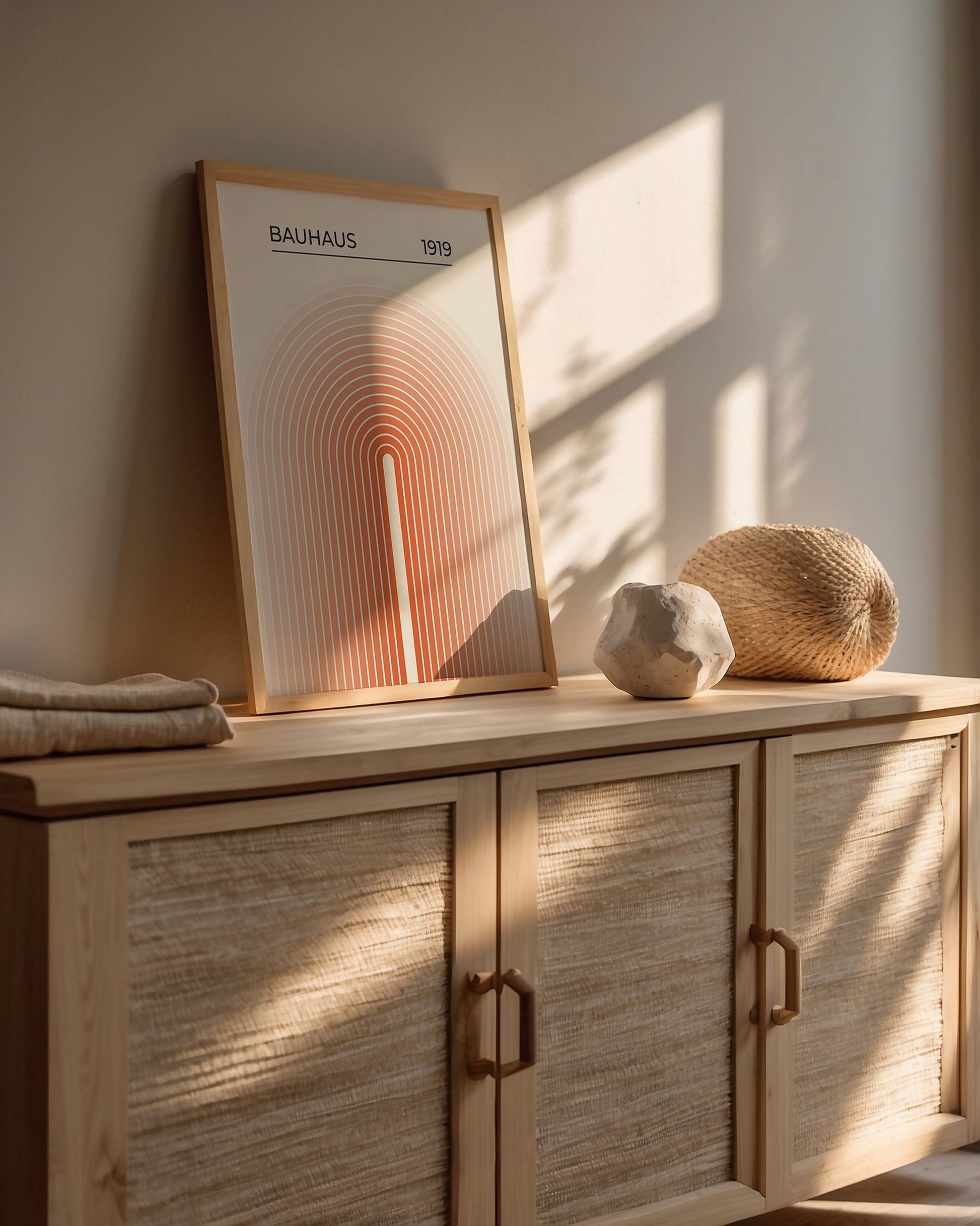 Bauhaus wall art print 'Sun Gateway' featuring concentric arches in orange and peach tones, styled in a modern home interior.