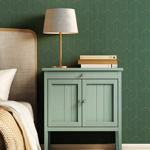 Art Deco wallpaper with golden chevron pattern on emerald green, paired with retro green cabinet and modern lamp.