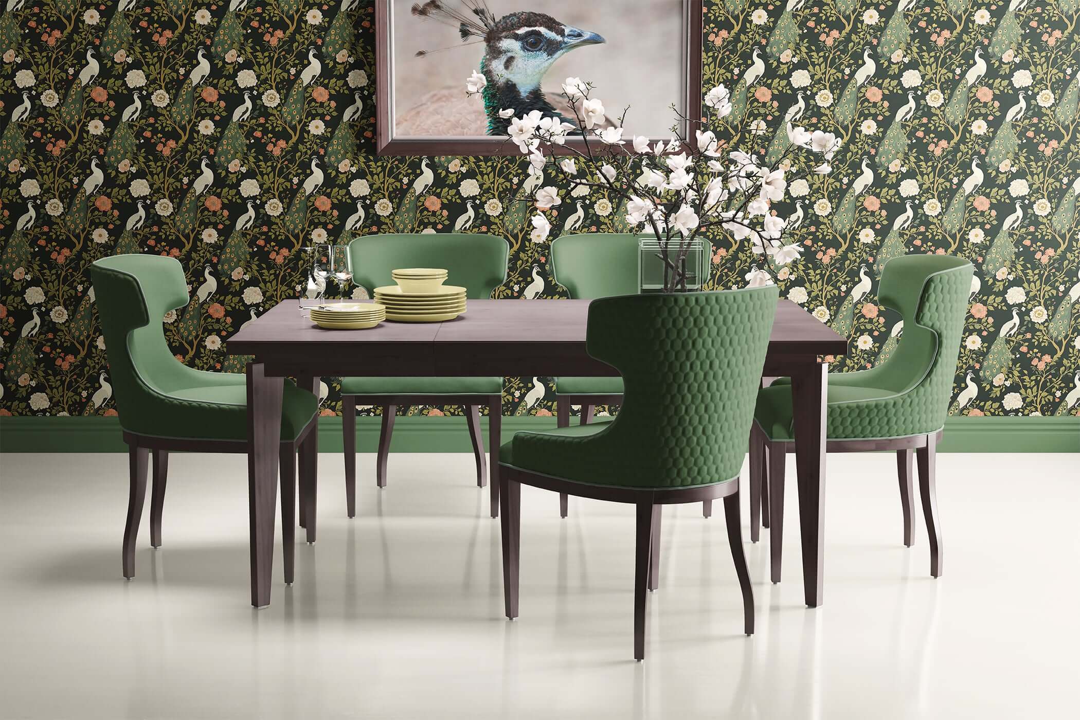 Art deco dining room with Mystical Garden Elegance wallpaper featuring peacocks and floral design, green chairs and dark wood table.